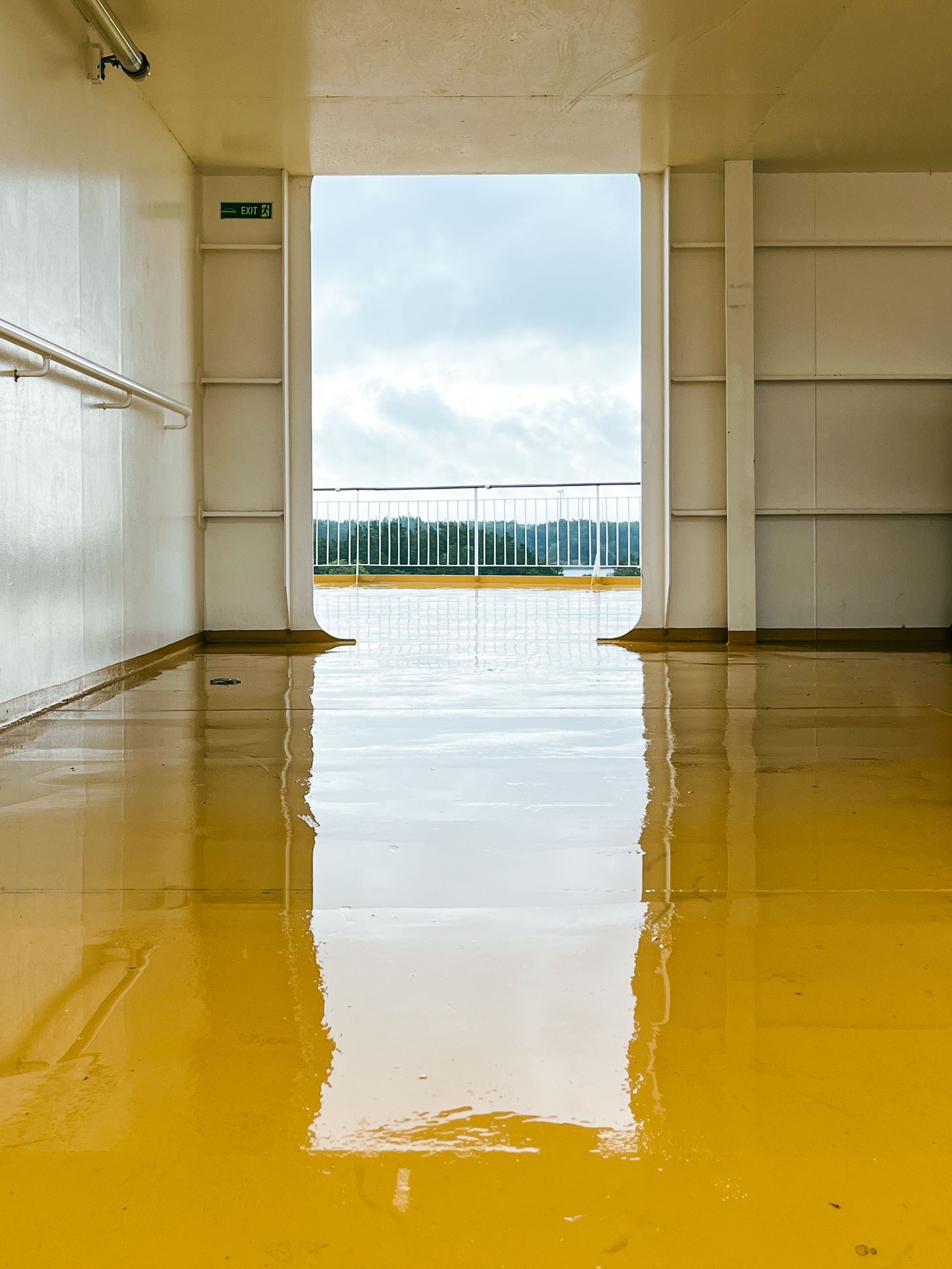 View from a ferry deck in Stockholm with wet yellow floor reflecting light.
